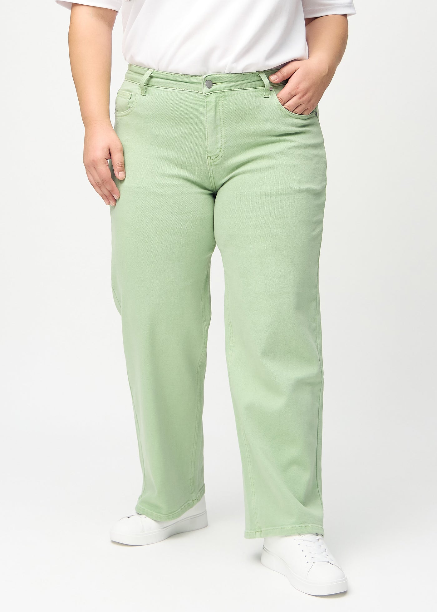 Lysegrønne loose jeans, modelnavn Mints, som er løstsiddende med masser af vidde i benene på en plus-size model, set forfra.