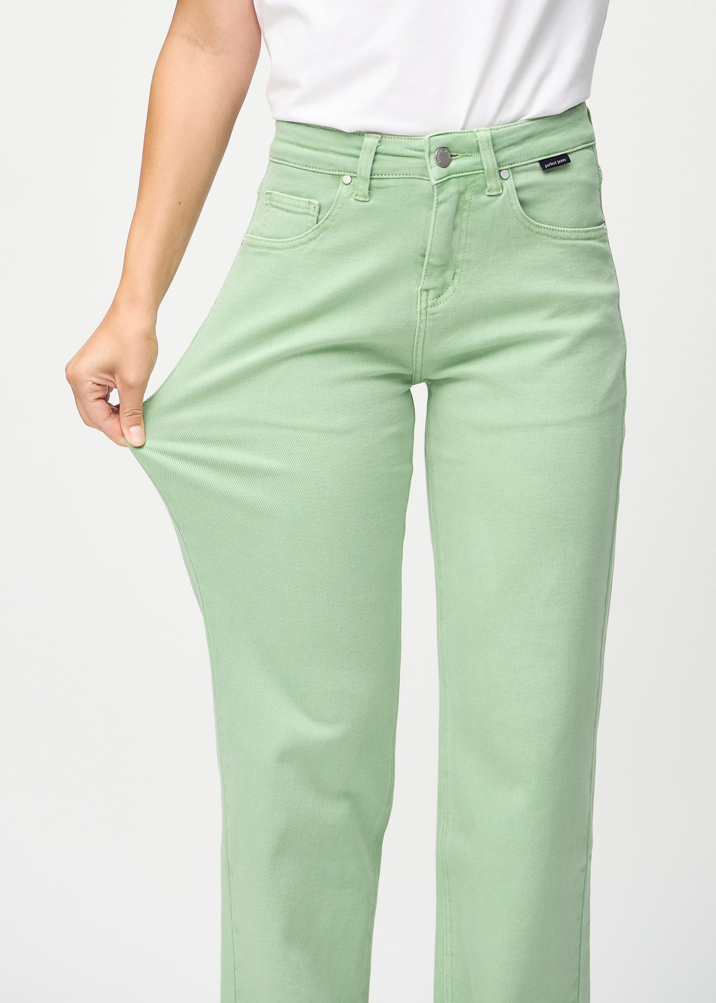 Model strækker jeansene ved låret for at vise stretch.