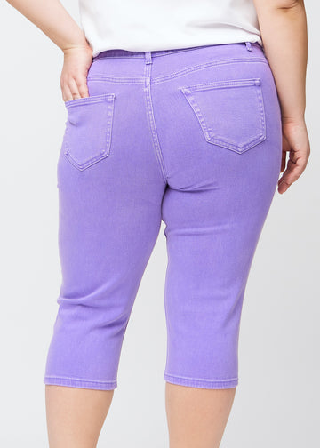 Tæt billede af bagdelen på en plus-size model i lilla slim capris – detaljefokus på lommer og syninger.