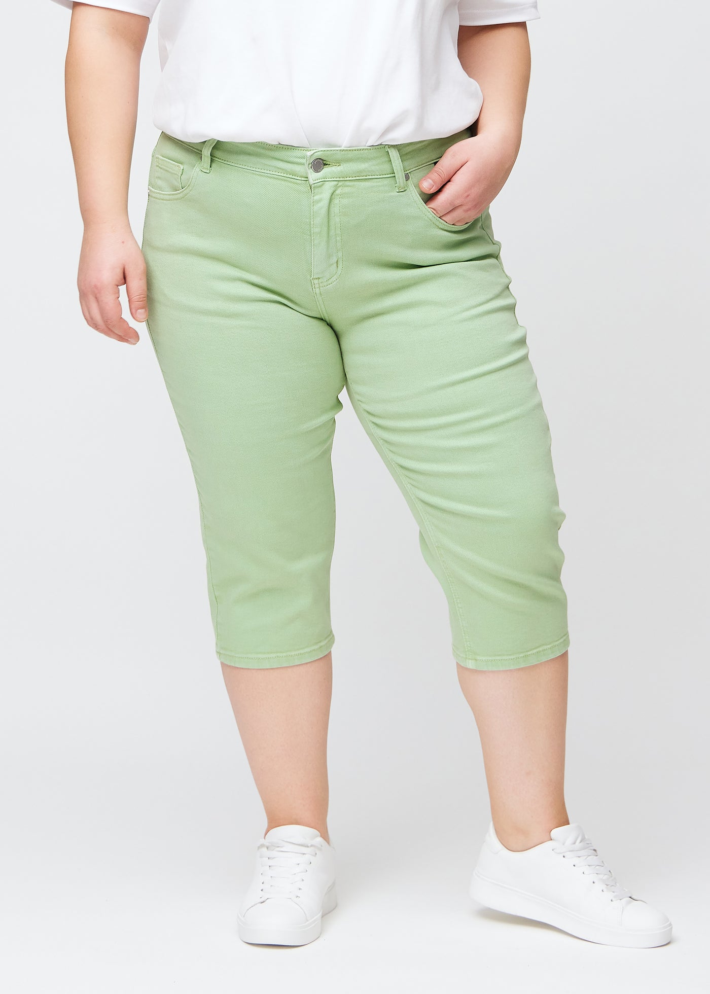 Lysegrønne slim capris, farve Mints, med tætsiddende pasform og længde lige under knæet – set forfra på plus-size model.
