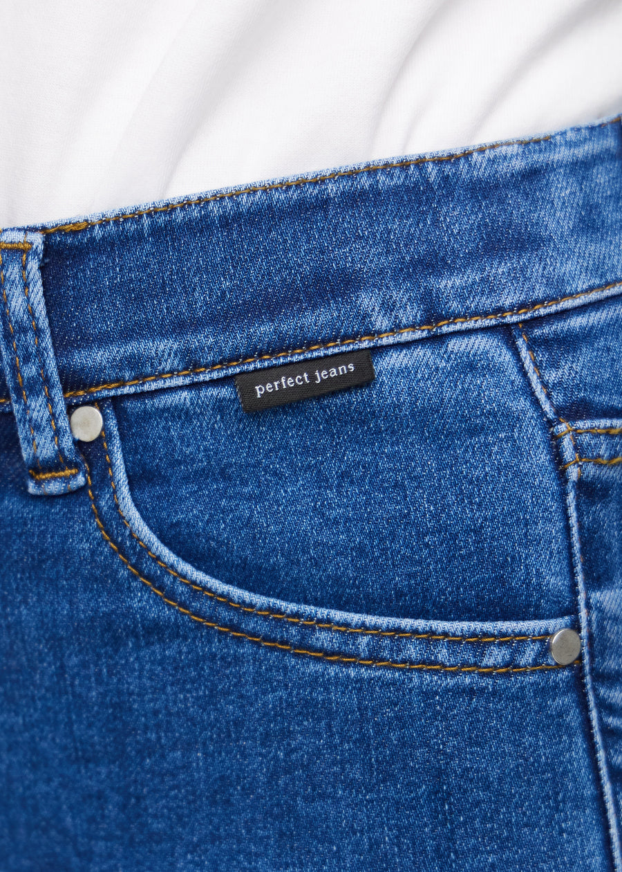 Nærbilde av mørkeblå denim med Perfect Jeans-logoetikett ved kanten av forlommen.