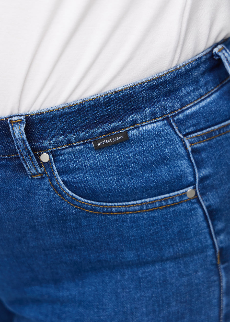 Nærbilde av mørkeblå denim med Perfect Jeans lærpatch bak i linningen.