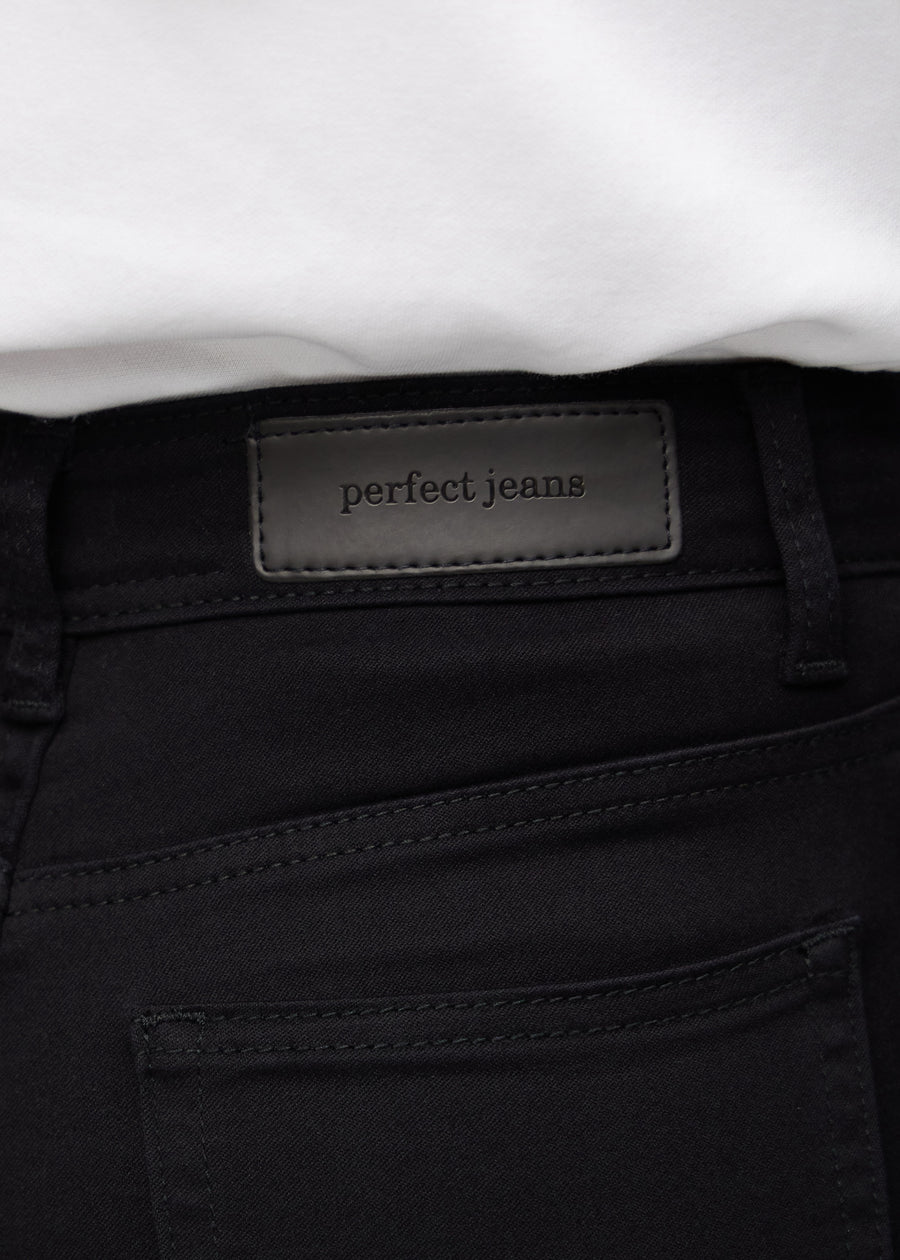 Nærbilde av sort jeansmateriale med Perfect Jeans lærpatch bak i linningen.