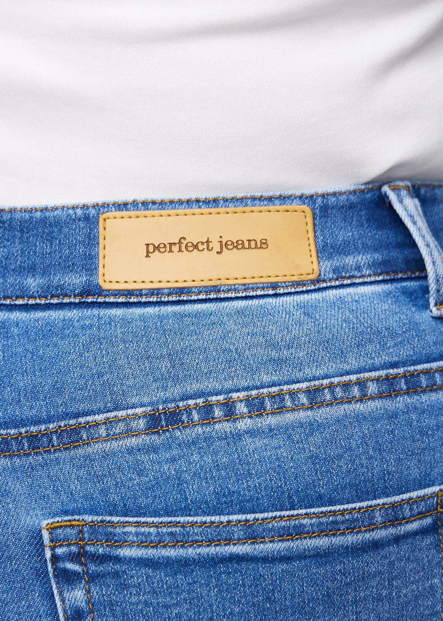 Nærbilde av blå denim med Perfect Jeans lærpatch bak i linningen på en plus-size modell.