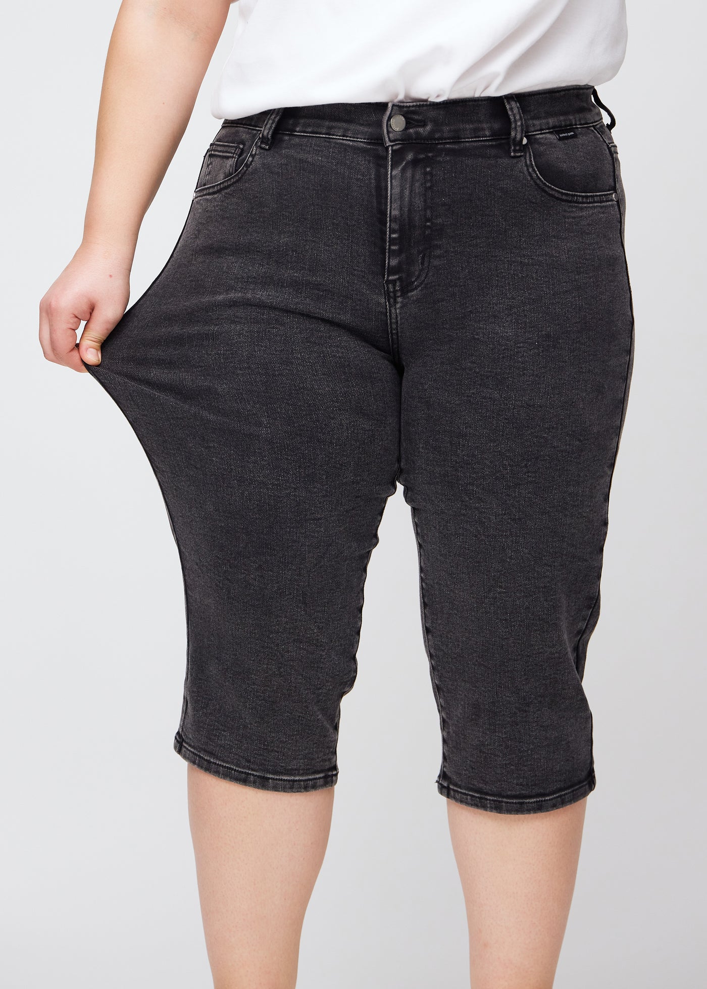 Plus-size model strækker caprisene ved låret for at vise stretch.