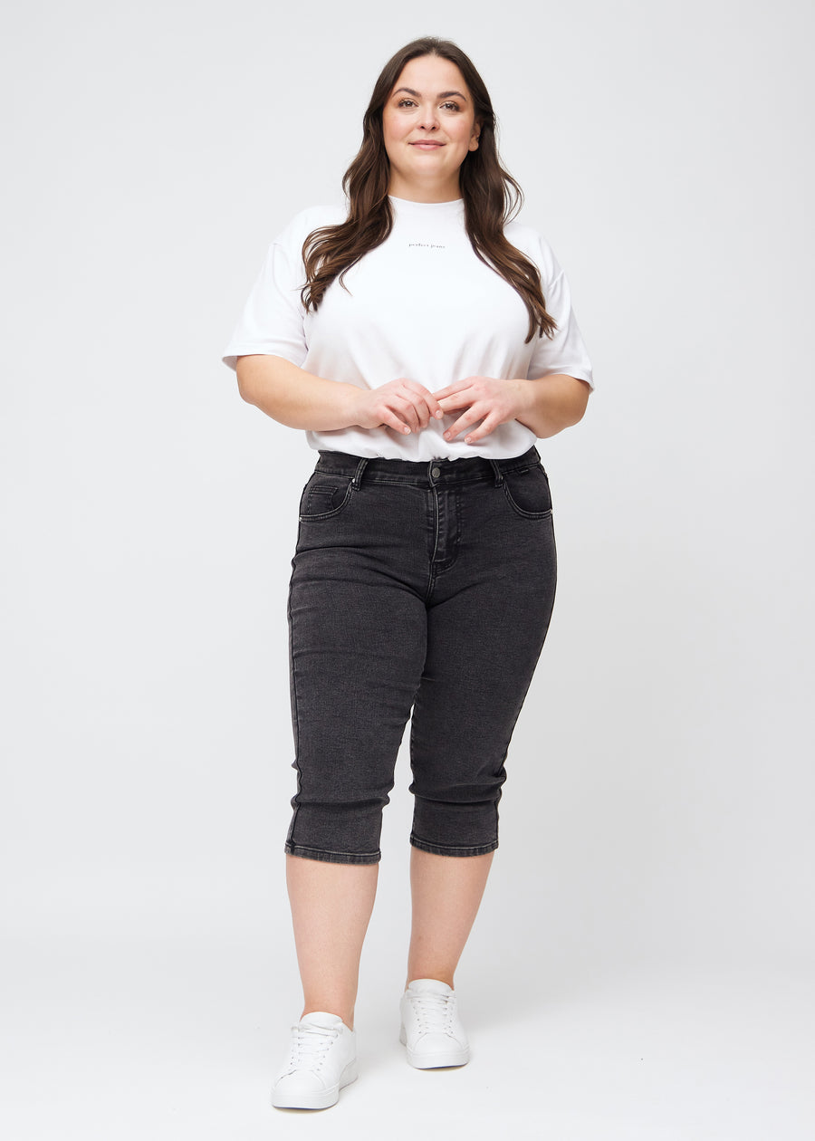 Fuldt billede af plus-size model i mørkegrå denim slim capris.