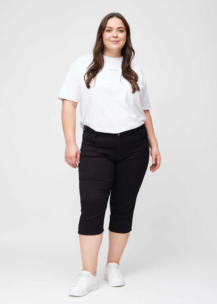 Fuldt billede af plus-size model i sorte slim capris.