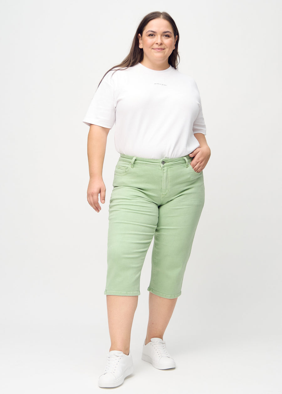 Plus-size model går ind i billedet, strækker i sine capris, viser dem frem ved at dreje rundt, og forlader derefter billedet.