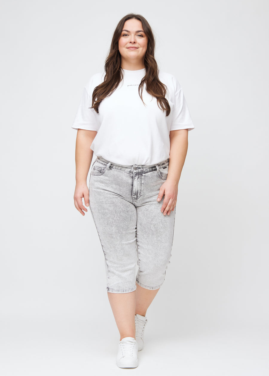 Plus-size model går ind i billedet, strækker i sine capris, viser dem frem ved at dreje rundt, og forlader derefter billedet.