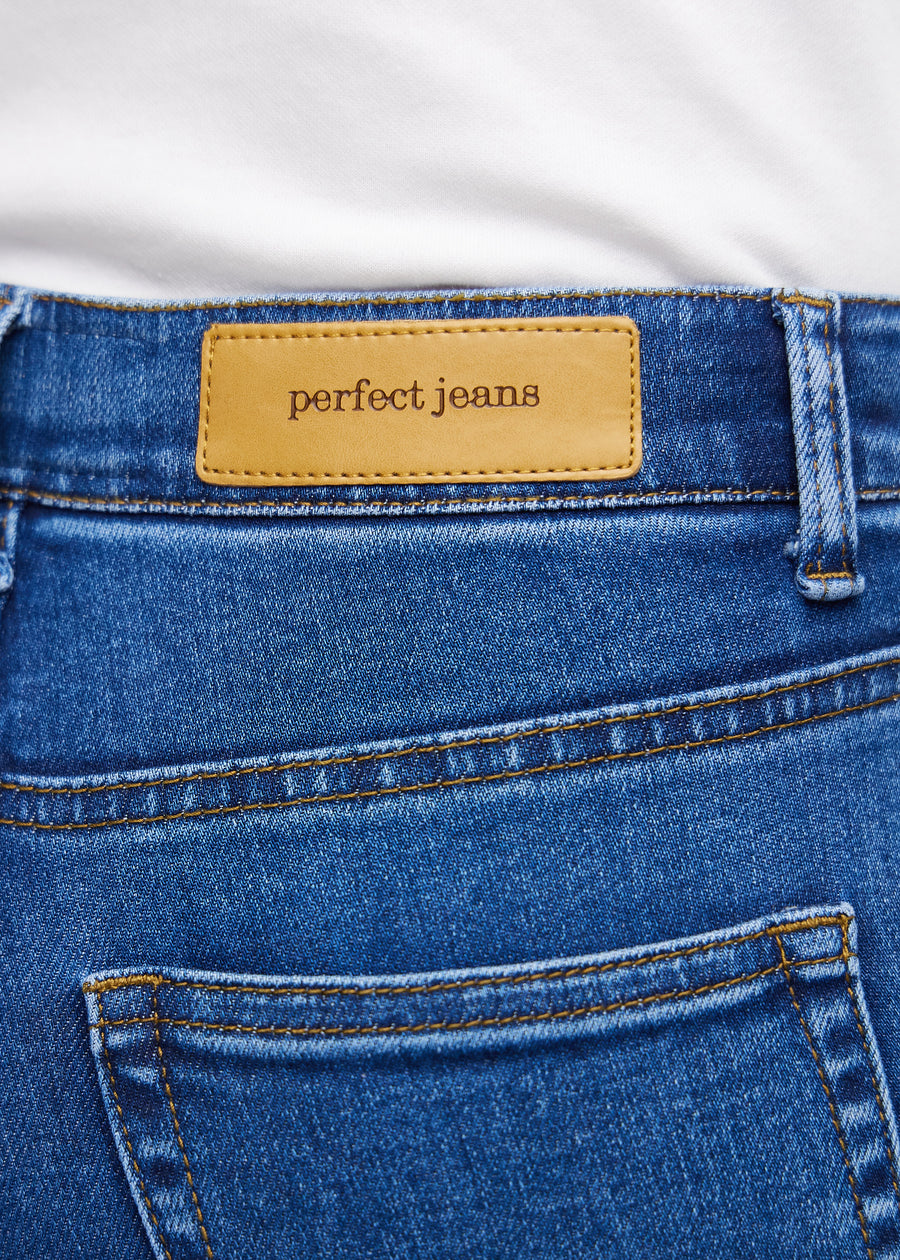 Nærbilde av mørkeblå denim med Perfect Jeans lærpatch bak i linningen.