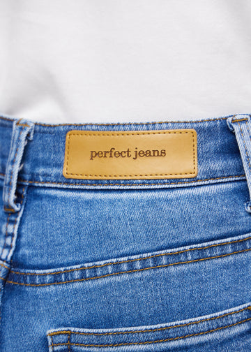 Nærbilde av blå denim med Perfect Jeans lærpatch bak i linningen.