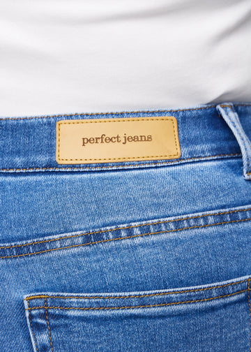 Nærbilde av blå denim med Perfect Jeans lærpatch bak i linningen på en plus-size modell.