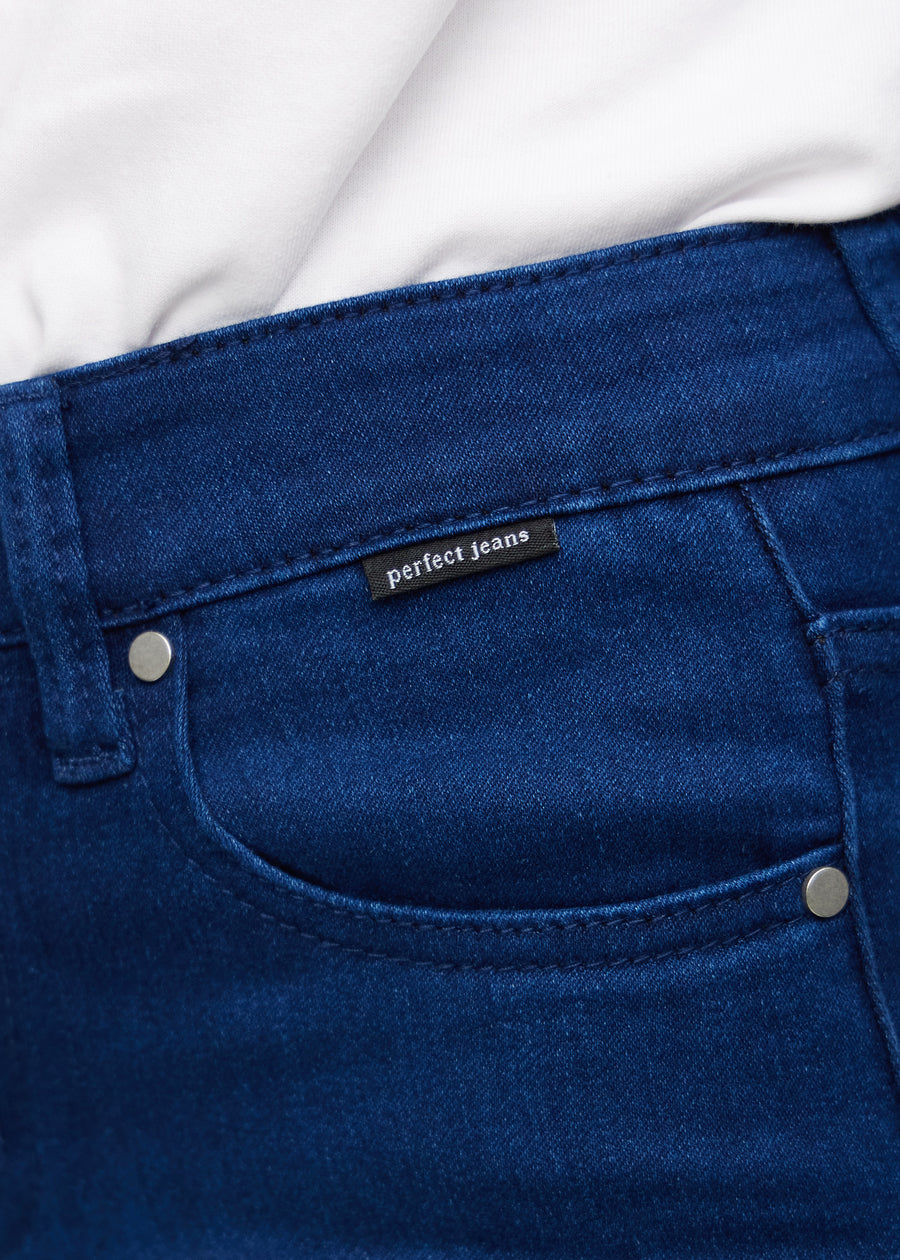 Nærbillede af mørkeblåt jeansmateriale med Perfect Jeans logoetiket ved forlommekanten.