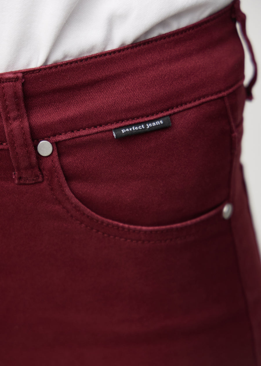 Nærbillede af rødt jeansmateriale med Perfect Jeans logoetiket ved forlommekanten.