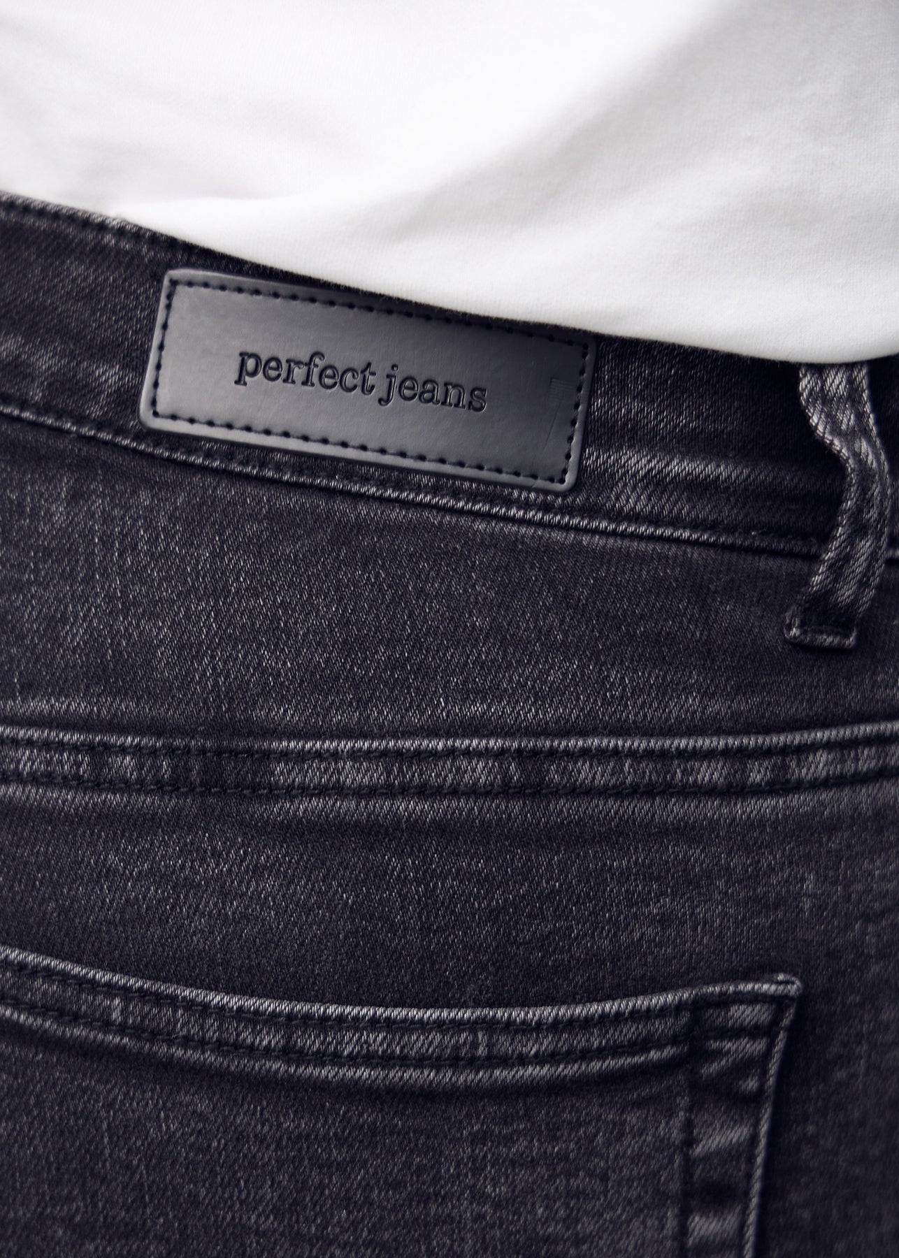 Nærbillede af mørkegrå denim med Perfect Jeans læderpatch bagpå i taljen.