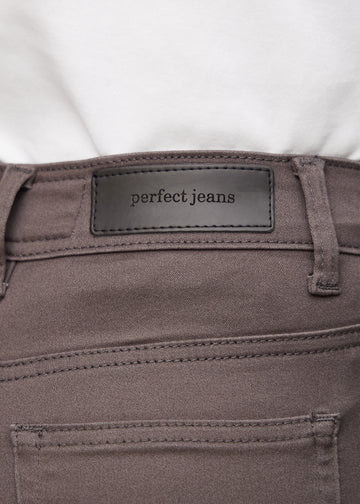 Nærbillede af gråbrunt jeansmateriale med Perfect Jeans læderpatch bagpå i taljen.