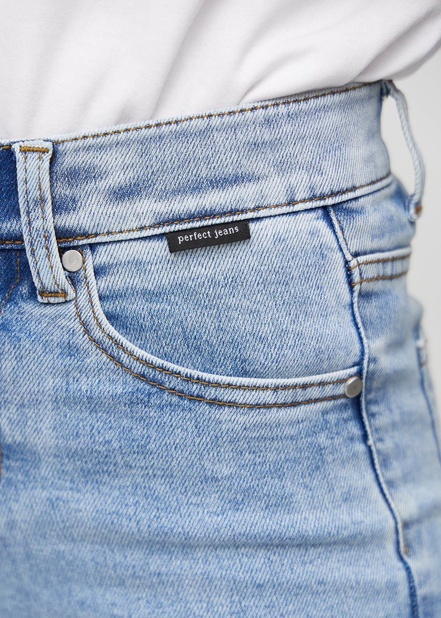 Nærbilde av lyseblå denim med Perfect Jeans logoetikett ved forkanten av lommen.
