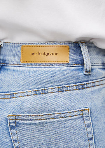 Nærbilde av lyseblå denim med Perfect Jeans skinnpatch bak i livet.
