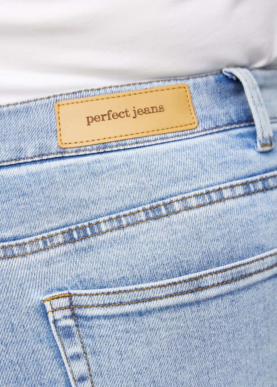 Nærbilde av lyseblå denim med Perfect Jeans skinnpatch bak i livet, på en plus-size modell.