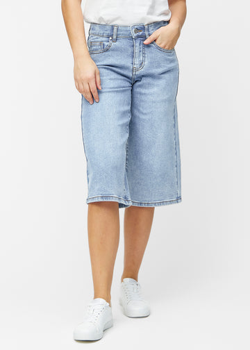 Løse, lyseblå denim capris i fargen Waves som sitter ved hoften og faller løst ned over lårene til rett under kneet, sett forfra.
