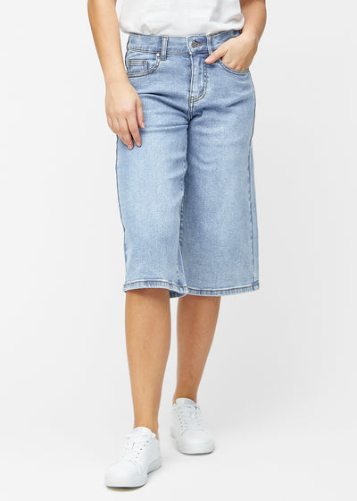 Løse, lyseblå denim capris i fargen Waves som sitter ved hoften og faller løst ned over lårene til rett under kneet, sett forfra.
