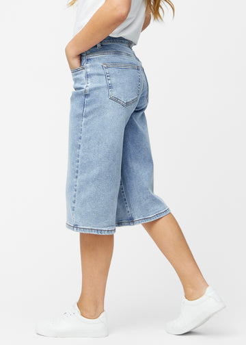 Løse, lyseblå denim capris i fargen Waves sett fra siden på modell, hvor den brede passformen og lengden til rett under kneet er synlig.