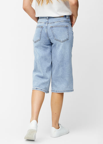 Løse, lyseblå denim capris i fargen Waves sett bakfra, slik at passform og lengde kan sees.