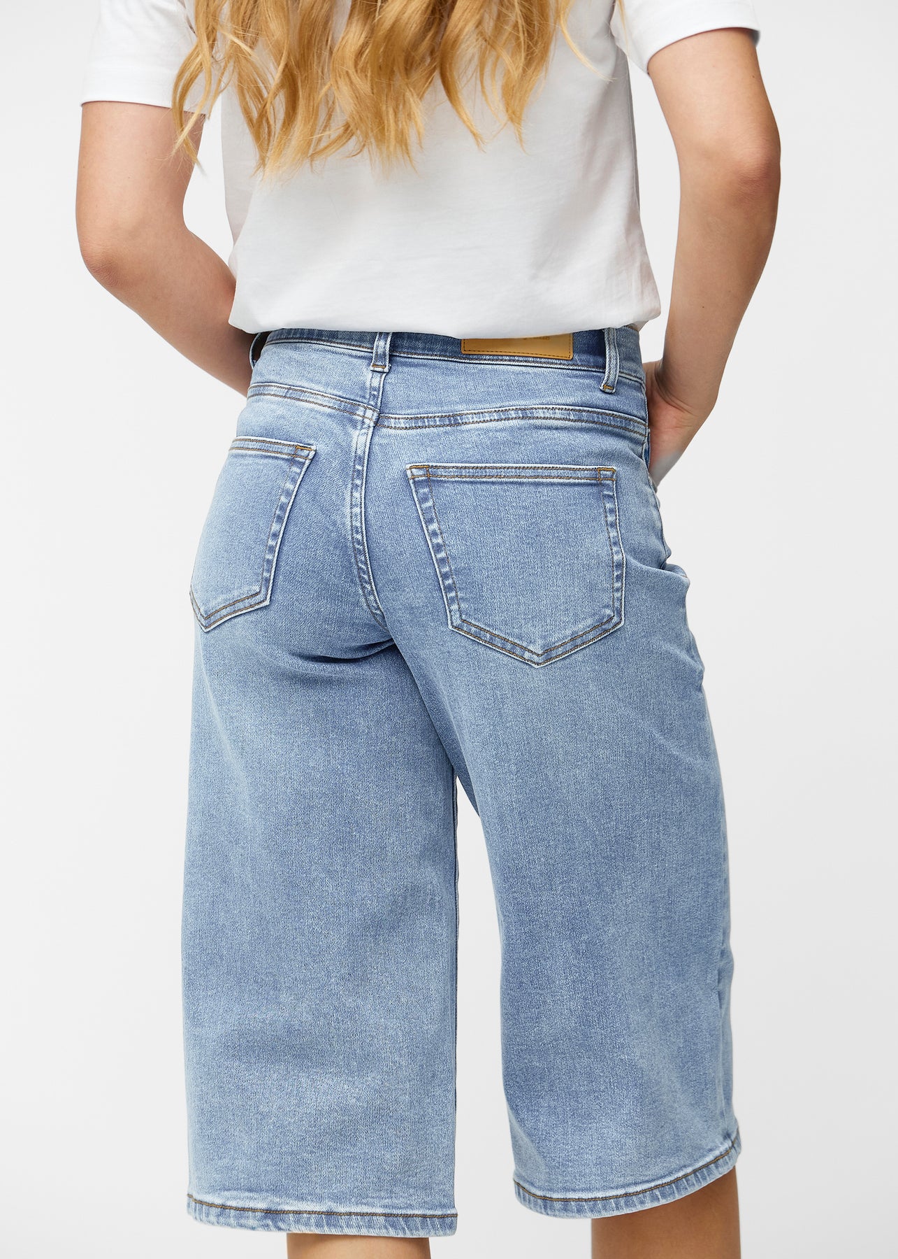 Løse, lyseblå denim capris i fargen Waves sett bakfra på nært hold for å vise passform og detaljer.