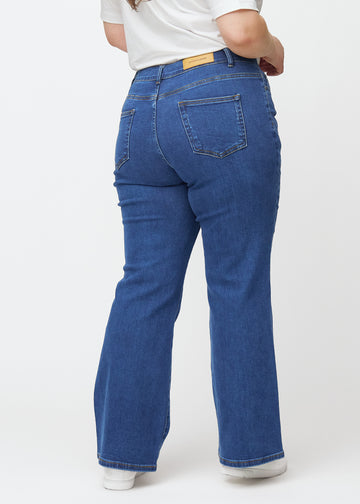 Mørkeblå mid-rise bootcut-jeans i fargen Oceans. Sett bakfra på en plus size-modell, slik at hele passformen vises.