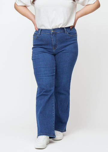 Mørkeblå mid-rise bootcut-jeans i fargen Oceans. Sett forfra på en plus size-modell, med tettsittende passform over hofter og lår og lett utsving nederst.