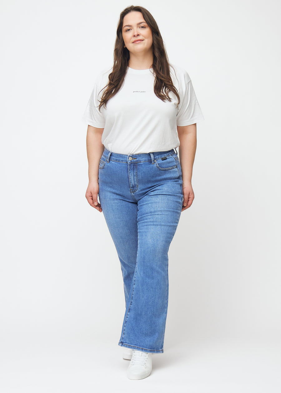 Blå mid-rise bootcut-jeans i fargen Rivers. Helhetsbilde av en plus size-modell med jeansene på.