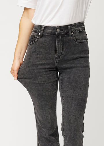 Mørkegrå mid-rise bootcut-jeans i fargen Shadows. En modell strekker jeansstoffet ved låret for å vise stretchen.