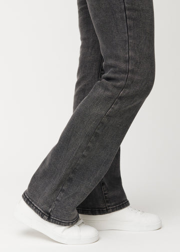 Mørkegrå mid-rise bootcut-jeans i fargen Shadows. Nærbilde ved ankelen på en modell som viser den lette utsvingen nederst.