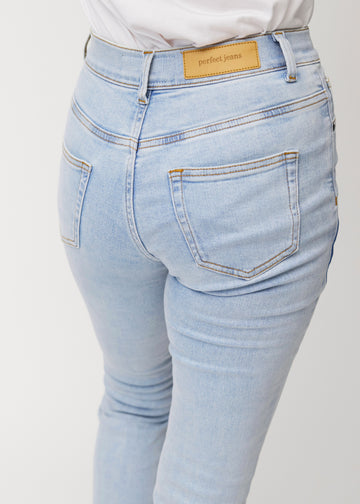 Lyseblå mid-rise bootcut-jeans i fargen Waves. Nærbilde bakfra på en modell for å vise detaljene.