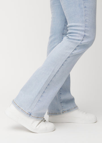 Lyseblå mid-rise bootcut-jeans i fargen Waves. Nærbilde ved ankelen på en modell som viser den lette utsvingen nederst.