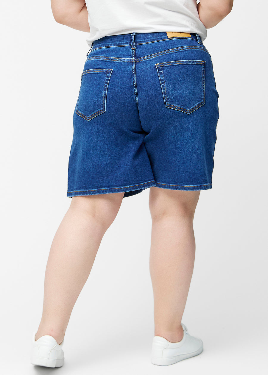 Løse, mørkeblå denim shorts i farven Oceans set bagfra på plus-size model, så pasform og længde kan ses.