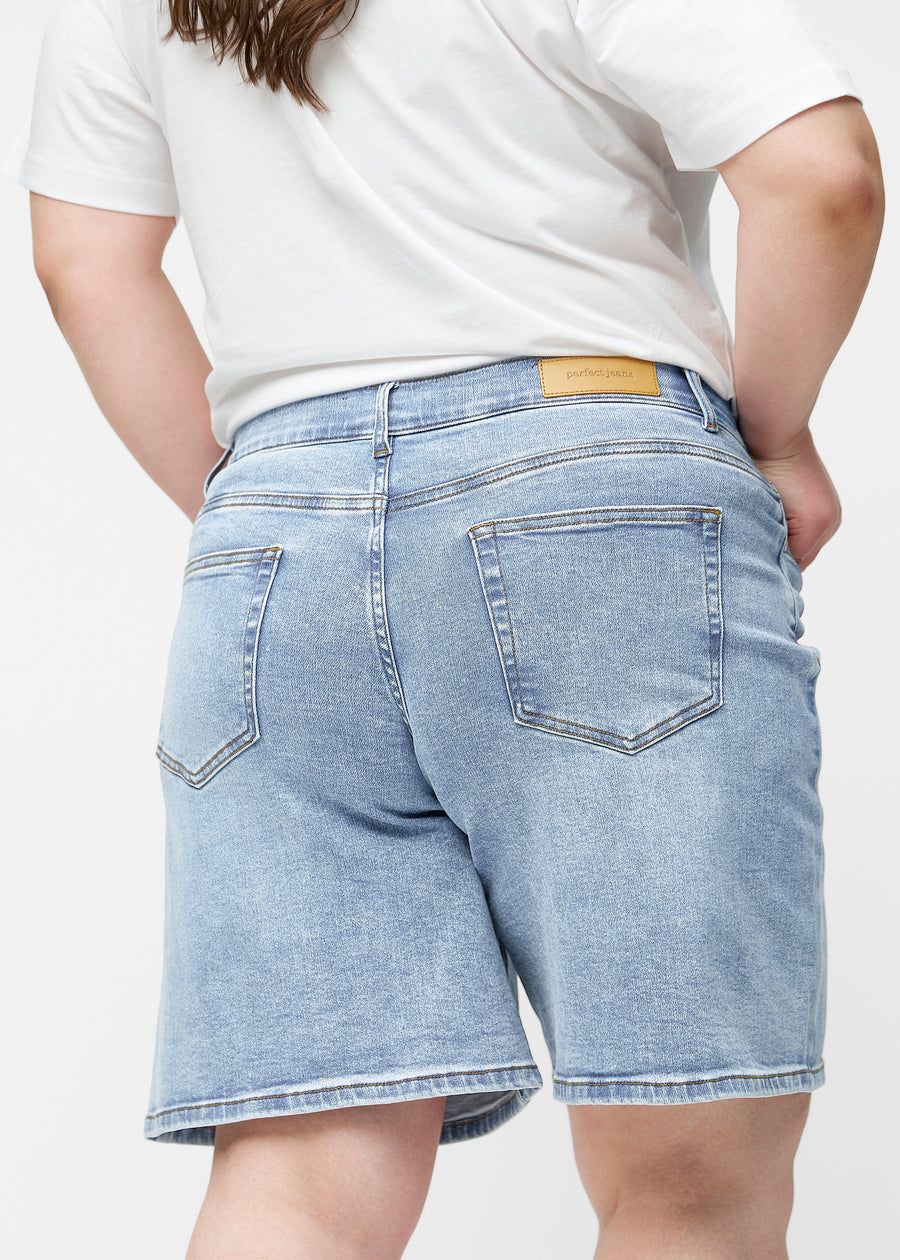 Løse, lyseblå denimshorts i fargen Waves sett bakfra på nært hold på plus-size modell for å vise passform og detaljer.