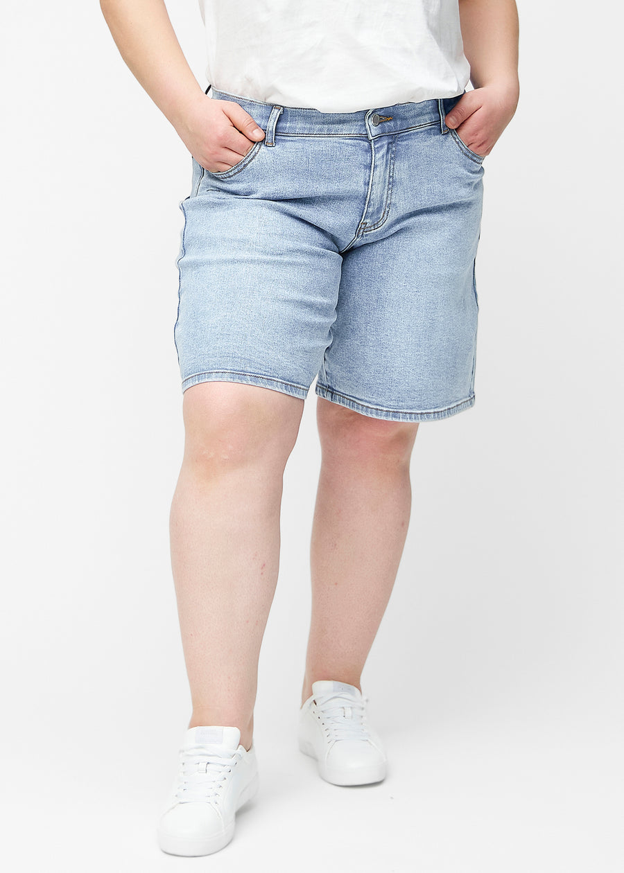 Løse, lyseblå denimshorts i fargen Waves sett forfra på plus-size modell, som sitter ved hoften og faller løst ned.