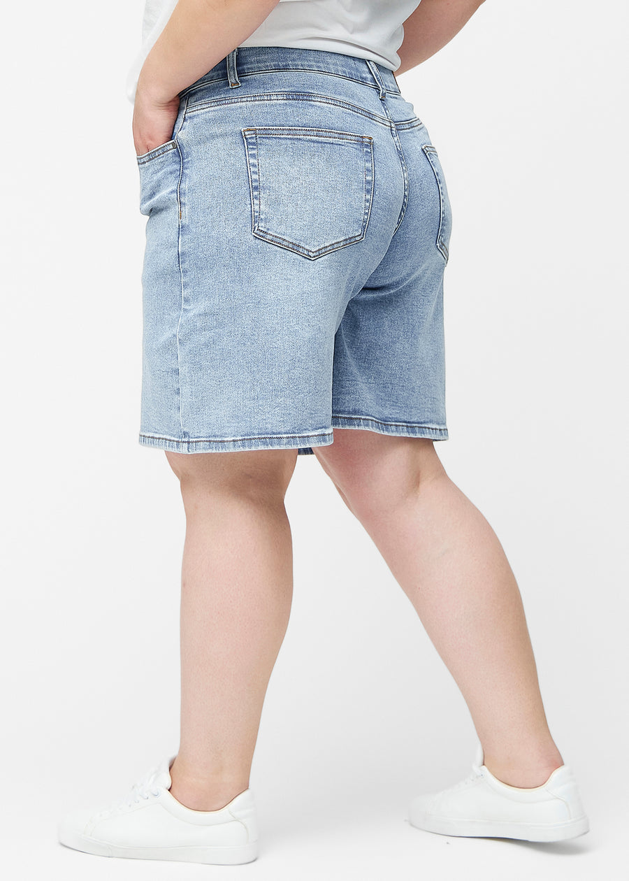 Løse, lyseblå denimshorts i fargen Waves sett fra siden på plus-size modell, hvor den brede passformen og lengden til rett over kneet er synlig.