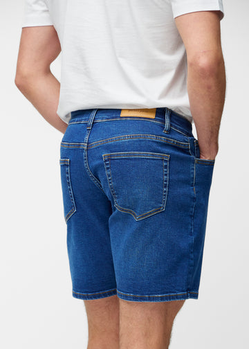 Mørkeblå denimshorts til herre i fargen Oceans sett bakfra slik at lengden til rett over kneet og passformen kan sees.