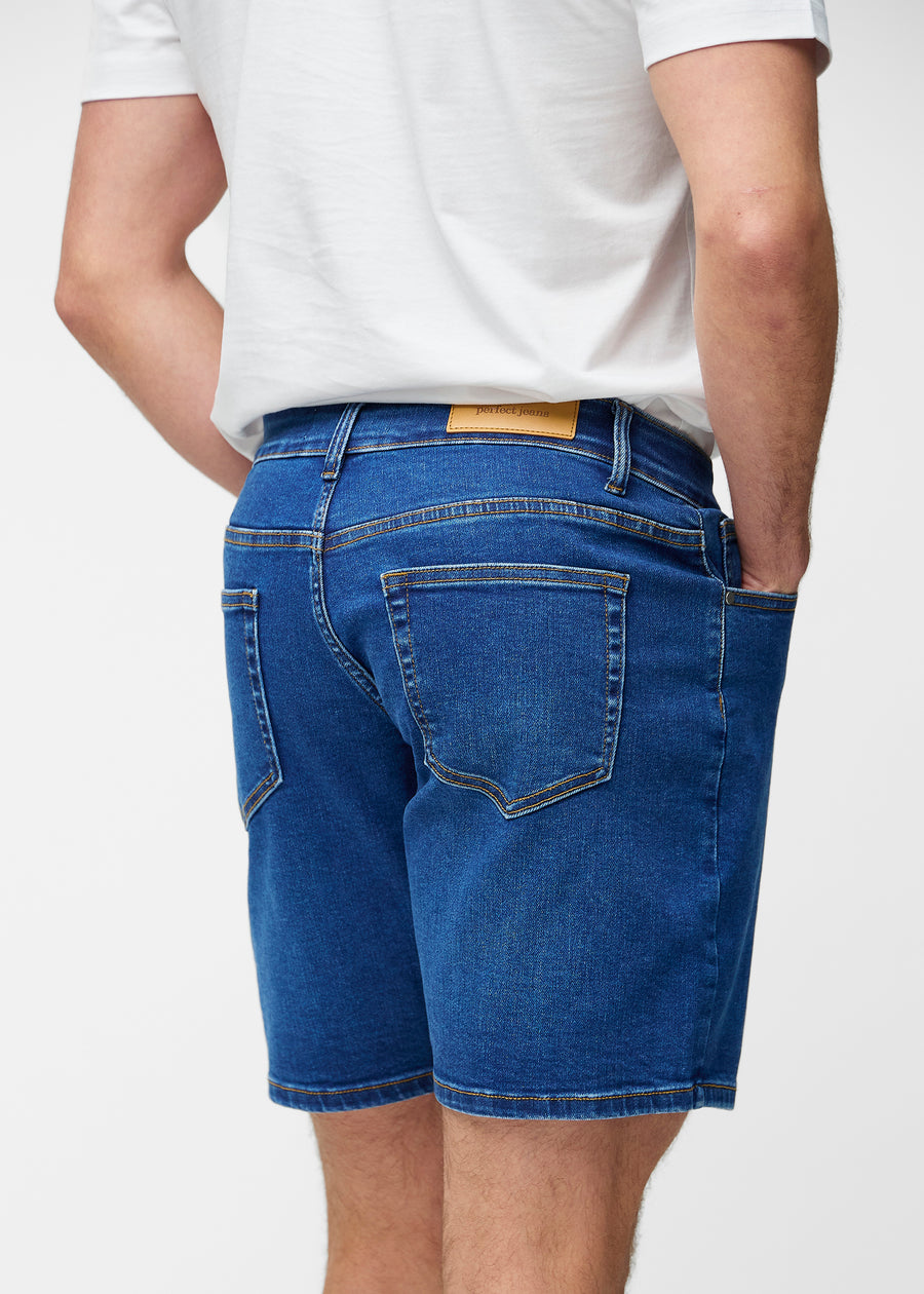 Mørkeblå denimshorts til herre i fargen Oceans sett bakfra slik at lengden til rett over kneet og passformen kan sees.