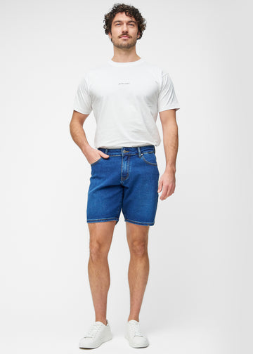 Fullt bilde av modell i mørkeblå denimshorts til herre i fargen Oceans med regular passform.