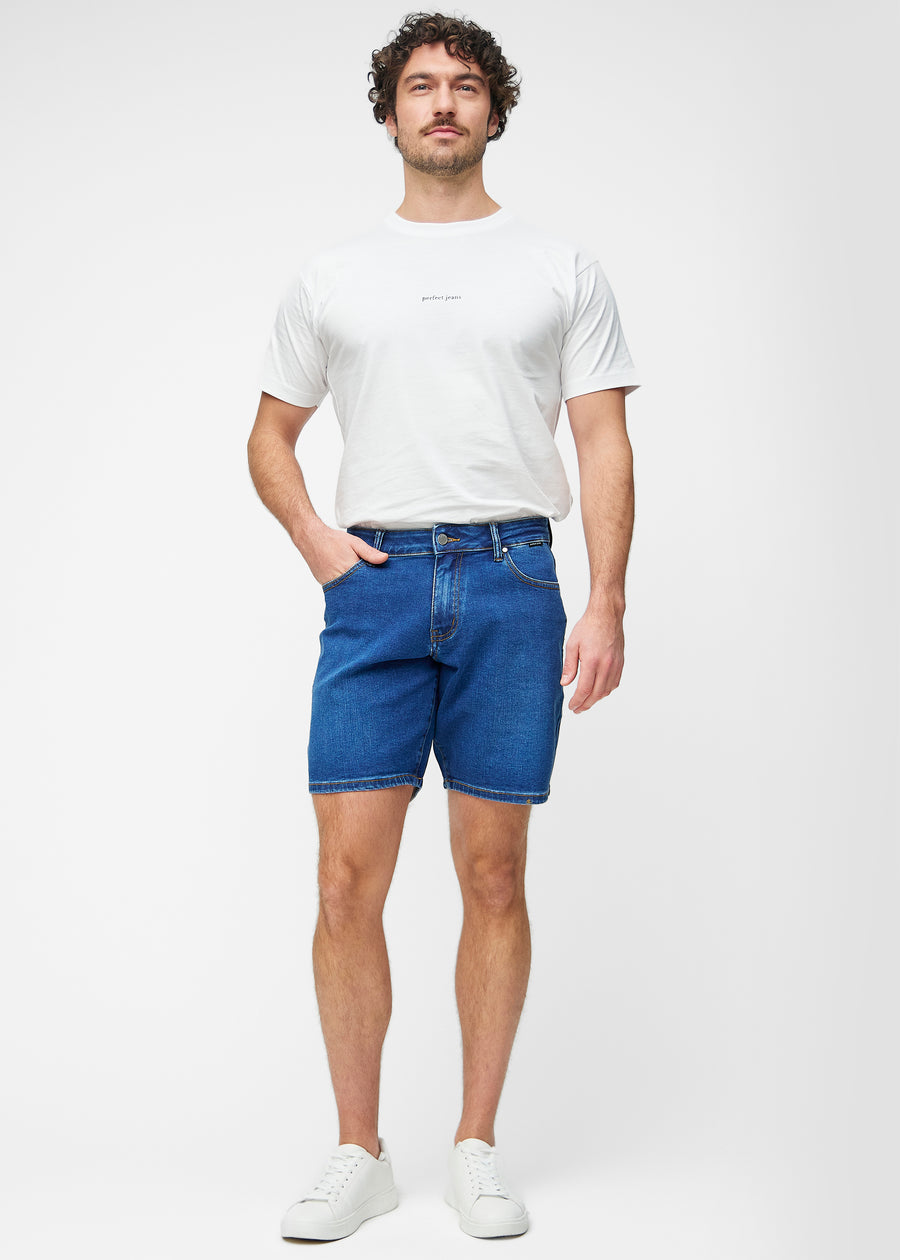 Fullt bilde av modell i mørkeblå denimshorts til herre i fargen Oceans med regular passform.