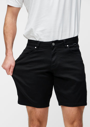 Modell strekker sorte shorts til herre i fargen Ravens ved låret for å vise materialets stretch.