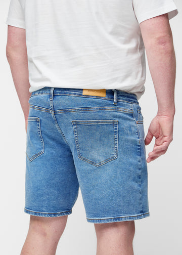 Blå denimshorts til herre i fargen Rivers sett bakfra på nært hold på plus-size modell for å vise passform og detaljer.