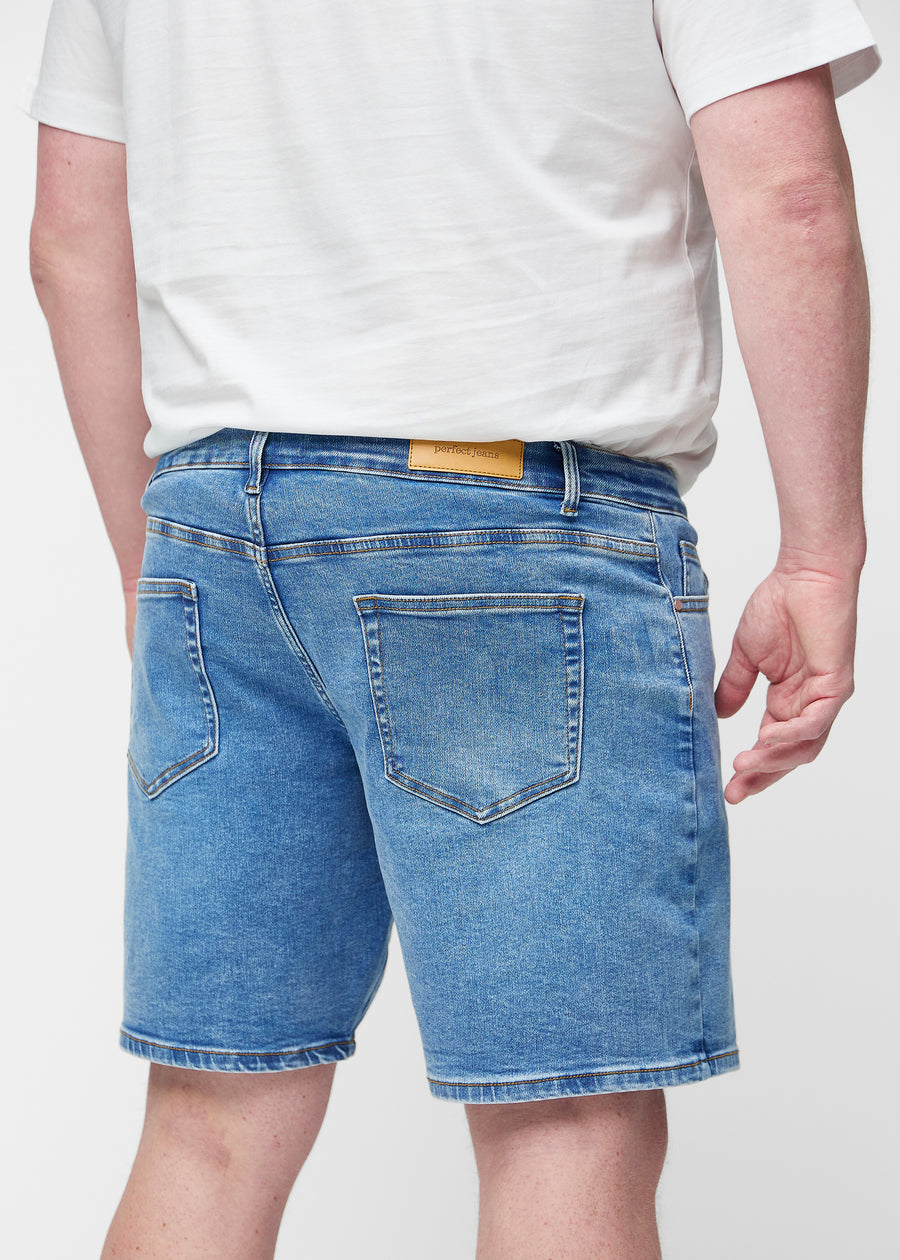 Blå denimshorts til herre i fargen Rivers sett bakfra på nært hold på plus-size modell for å vise passform og detaljer.