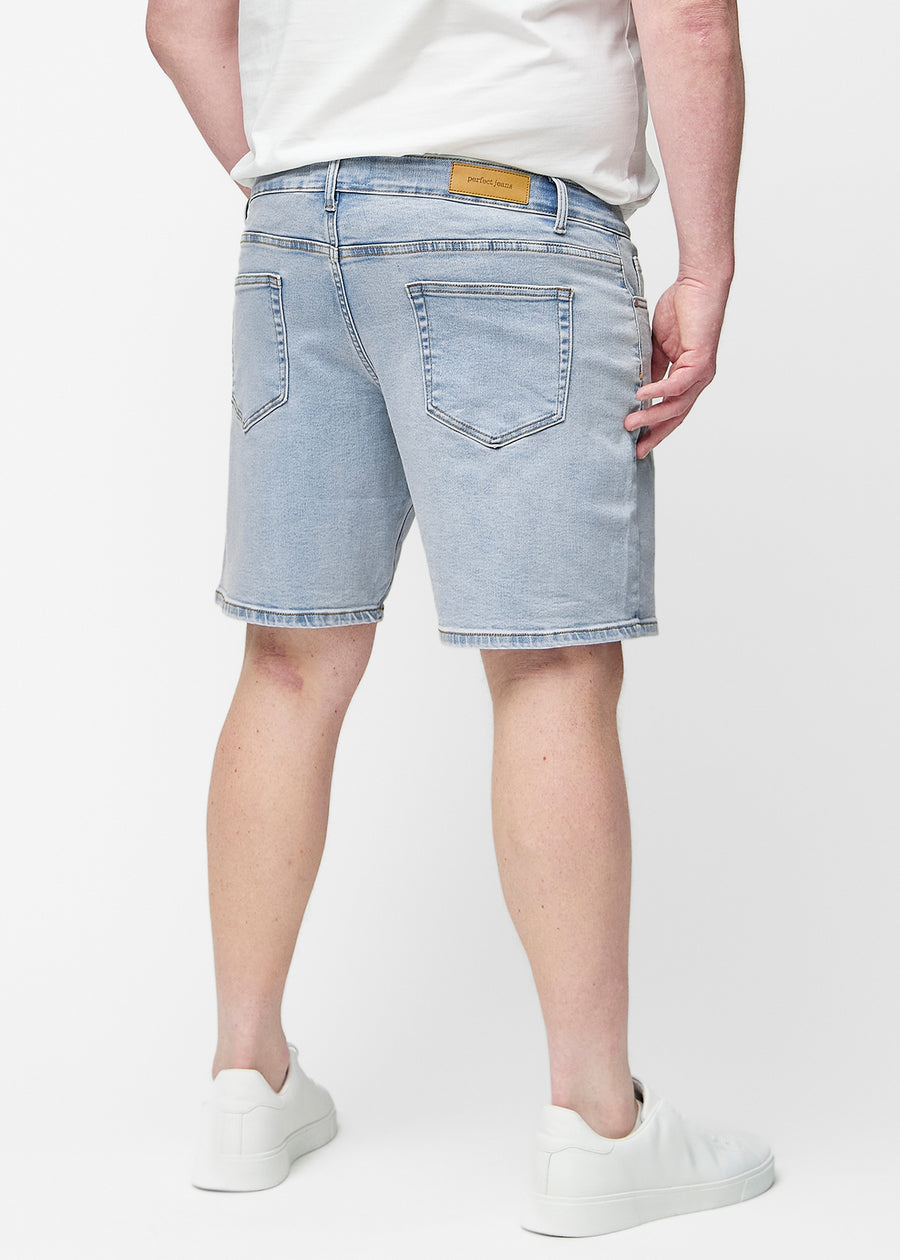 Lyseblå denimshorts til herre i fargen Waves sett bakfra på plus-size modell, slik at lengden til rett over kneet kan sees.