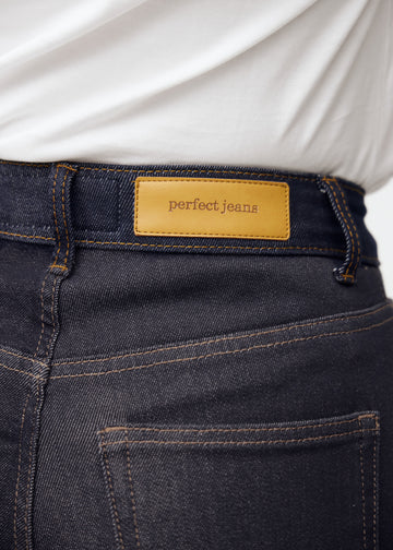 Nærbilde av dyp mørkeblå denim med Perfect Jeans lærpatch bak i midjen.