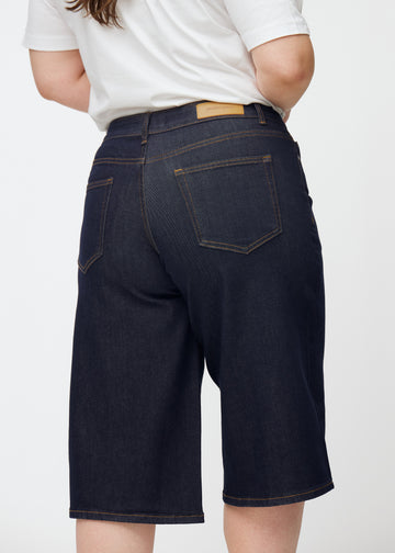 Dyp mørkeblå denim capris til dame i fargen Midnights sett bakfra i nærbilde på plus-size modell.