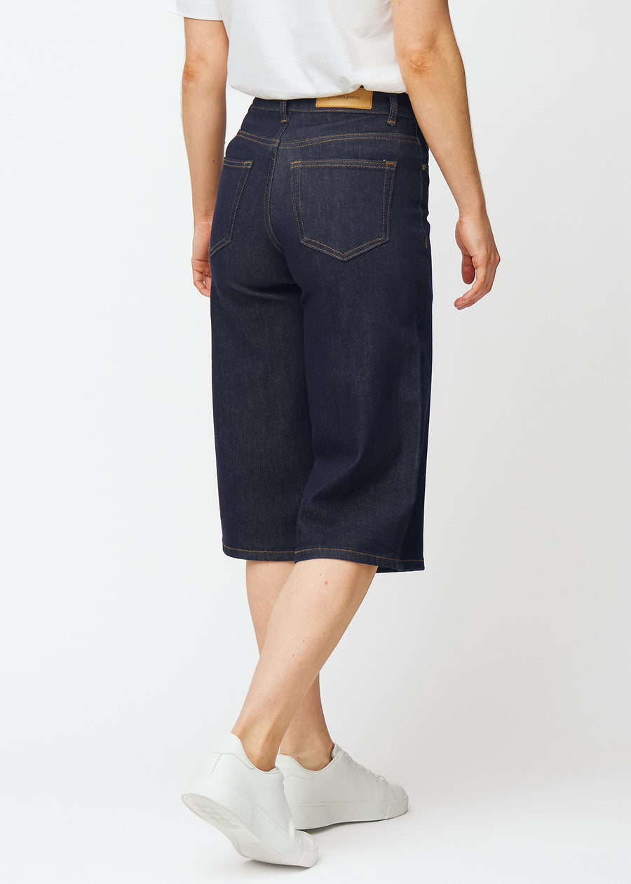 Dyp mørkeblå denim capris til dame i fargen Midnights sett bakfra, slik at lengden under kneet vises.